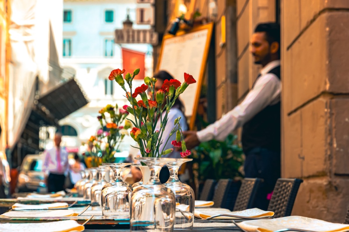 Ein Kellner bedient Tische vor einem Restaurant